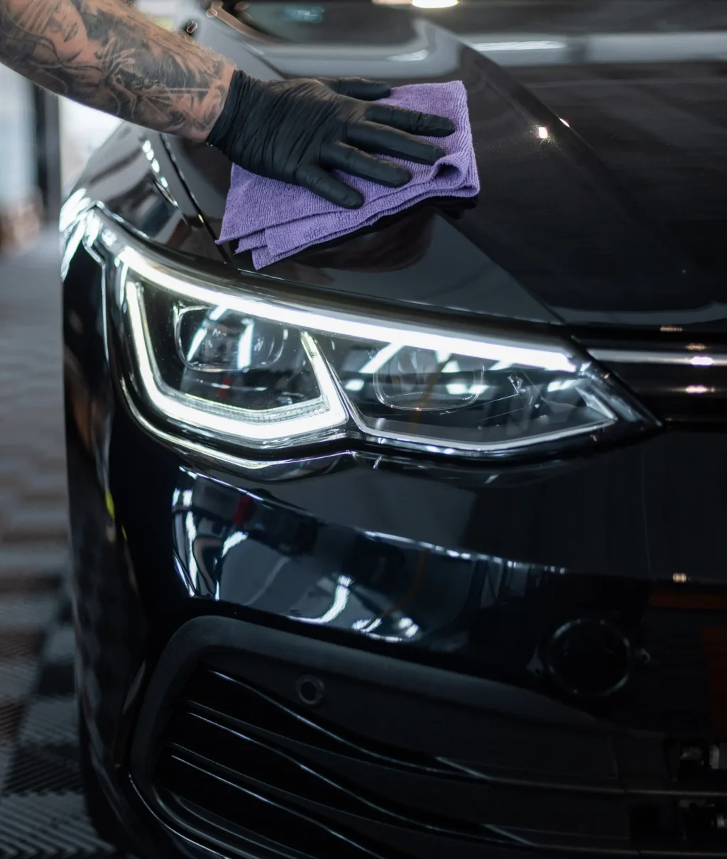 man-wipes-black-car-dry-with-cloth-detailing-car-care-washing